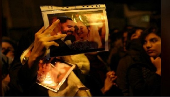 A woman holds a picture of newlyweds, victims of the crash of the Boeing 737-800 plane