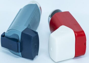 Two asthma inhalers with a white background lying next to each other.