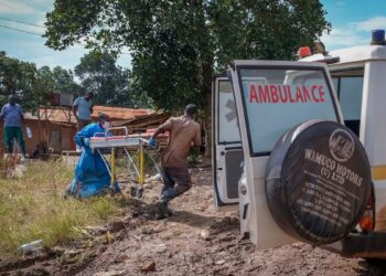 Men carry a stretcher used for suspected Ebola victims back to an ambulance after washing it, in the town of Kassanda in Uganda (Image: Hajarah Nalwadda/AP/REX/Shutterstock)
