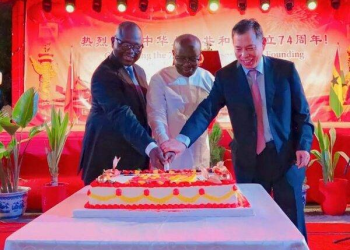 Mr Ken Ofori-Atta (middle) being assisted by Mr Lu (right) and Mr Asenso-Boakye to cutting the cake