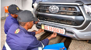 Mechanics fixing a new numberplate on a vehicle in Kampala, Uganda on November 1, 2023.